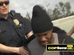 Black criminal is getting his huge cock sucked hard by two horny MILF cops